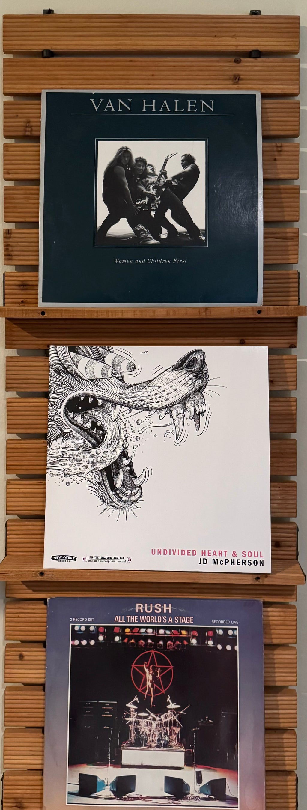 Three album covers of Van Halen, Rush, and JD Pherson on a custom wooden shelf to hold album covers.
